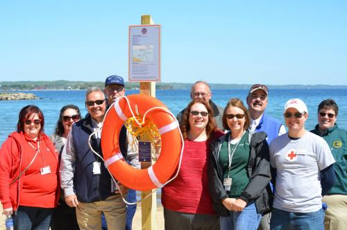 Staff and volunteers pose in front fo a safety ring and post. Photo credit: Michigan Sea Grant